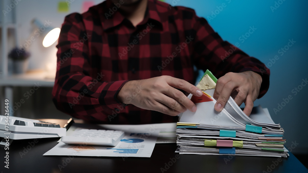 Poster A man is sitting at a desk with a stack of papers in front of him