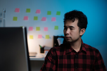 A man is sitting in front of a computer monitor with a green