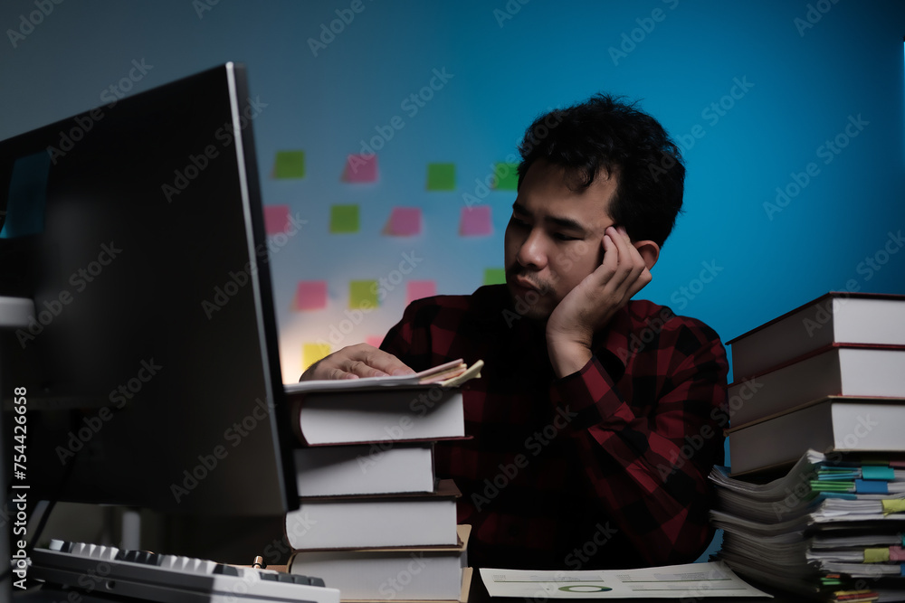 Poster A man is sitting at a desk with a computer monitor and stacks of books