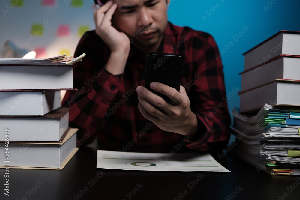 Poster a man is sitting at a desk with a stack of books and a cell phone