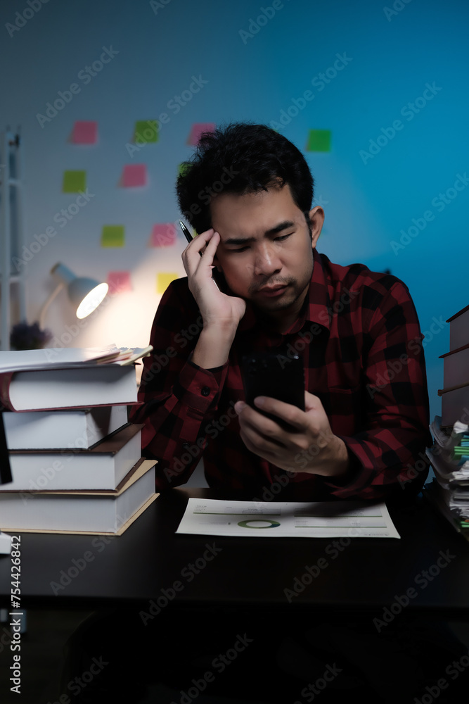 Poster a man is sitting at a desk with a stack of books and a cell phone