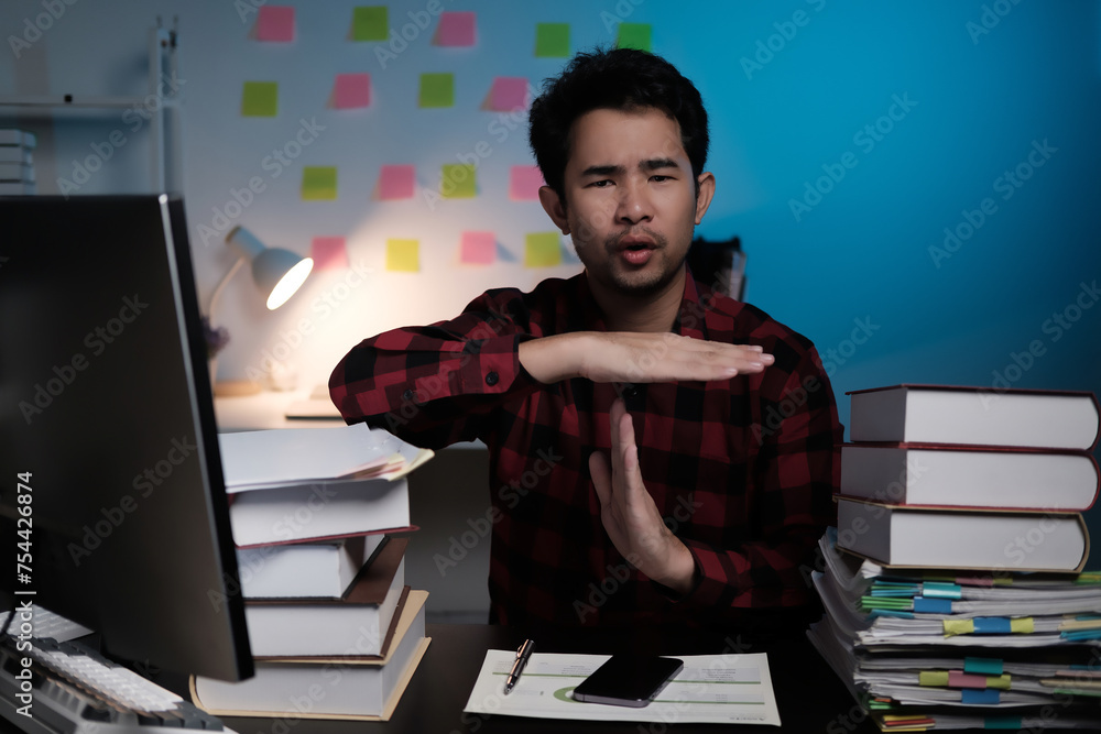Poster A man is sitting at a desk with a computer monitor and stacks of books