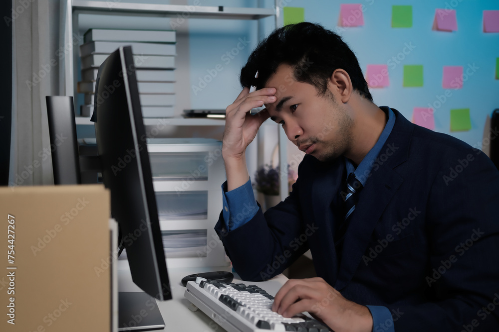 Poster A man is sitting at a desk with a keyboard and a computer monitor
