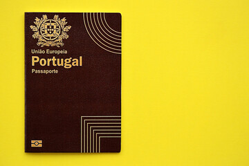 Red Portugal passport of European Union on yellow background close up. Tourism and citizenship concept