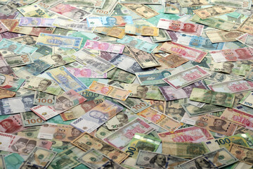 Many banknotes of different currency. Background of big amount of random money bills close up
