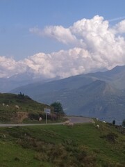Scenic Mountain Drive: Curvy Road in the Pyrenees with Sheep Grazing Alongside, Beneath a Blue Sky and Fluffy White Clouds
