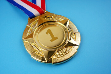 Motivational and inspirational concept. A gold medal placed on blue background.