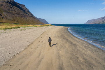 Holtsfjara - Iceland. Girl walking alone on sandy beach close to Önundarfjörður Pier in Westfjords, Iceland. Beautiful nature and travel destination