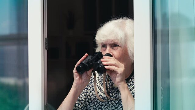 Humorous elderly woman watching people on the street using binoculars, spying