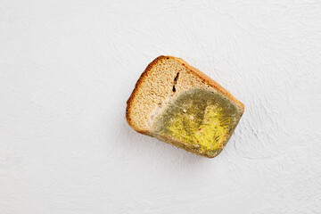 Moldy bread. Wasted, spoiled and moldy food on a gray background. Refusal to eat, irrational consumption.