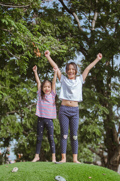 Happy 2 asian chlidren playing together in the park at daytime.