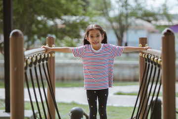 Little girl having fun on the playground in the park, outdoor shot.