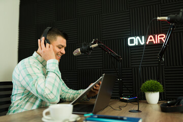 Cheerful man with a script enjoying recording a podcast