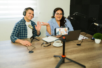 Cheerful podcast co-hosts live streaming their show in the studio