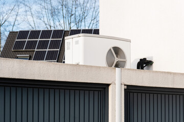 Wärmepumpe auf einem Garagendach eines Neubaugebiets, im Hintergrund sind Solarpanele auf Hausdächern montiert, Monheim am Rhein, NRW, Deutschland