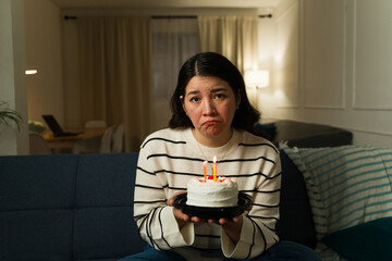 Depressed woman with a birthday cake at home celebrating at home