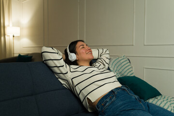 Relaxed woman listening to music with headphones on the couch