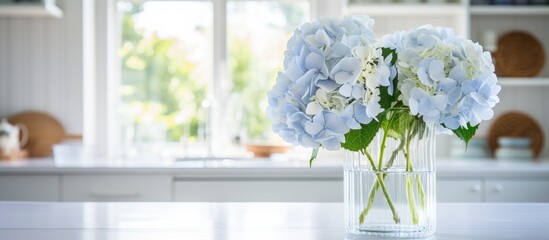 A glass vase sits on a kitchen table, brimming with a colorful assortment of blue and white hydrangea flowers, adding a touch of freshness and vibrancy to the space.