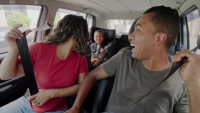 Family, transport, safety, road trip and people concept. Happy man and woman with little child driving in car. Auto tourism. Safety riding car concept wide angle inside car view image.
