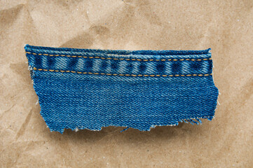 Scrap of grunge denim material close up on brown paper background