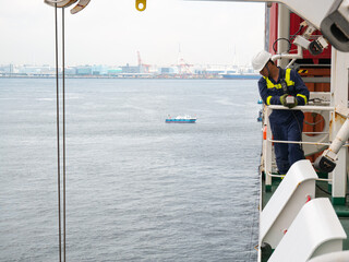 Seaman crew member of cargo vessel  equipped with personal protective equipment operate life boat...