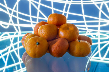 A pile of mandarins on a table. The mandarins are piled on top of each other. The mandarins are all...