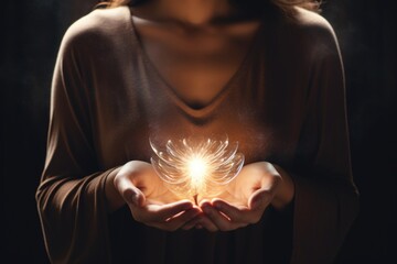 A woman holding a glowing feather, suitable for mystical or spiritual concepts - obrazy, fototapety, plakaty