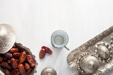 Top view on silver plate with date fruits and glass of water on a white wooden background. Ramadan background. Ramadan kareem. - 754488001