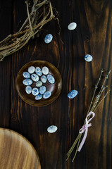 Easter composition. Blue eggs on wooden plate with dried lavender on dark vintage wooden background with willow wreath. Copy space.