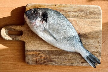 A whole raw Dorado fish lies on a wooden board. cooking at home. view from above. recipe
