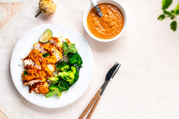 Crispy chicken cutlet with katsu sauce, with white rice and broccoli on a stone table.