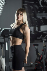 Fototapeta na wymiar Portrait of a young beautiful blonde sportswoman in the gym.