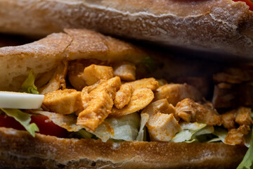 Close-up of chicken sandwich with lettuce, tomato and egg