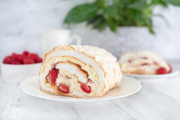 Meringue roll with strawberries and raspberries on white wooden table.  