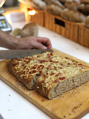 chef cutting a pizza in baguette on a wooden board