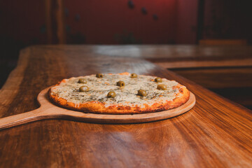 Cheese pizza with olives on a wooden table.