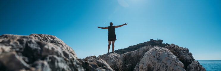 A male tourist is relaxing on a rocky coast on a hot day.