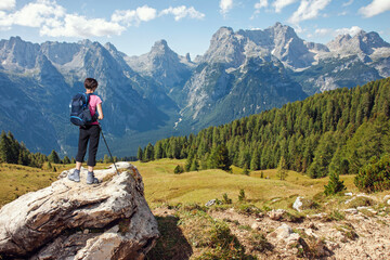 Woman hiker standing on stone rock and looking at scenic mountains in summer - 754522211
