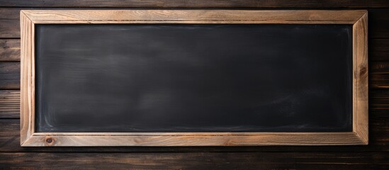 A black chalkboard menu with a wooden frame is mounted on a wooden wall. The blackboard is positioned near a restaurant, offering a space for a banner with a chalkboard restaurant menu mockup.