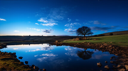 Fototapeta premium Night landscape with a tree and its reflection in the water in blue and green colors