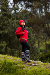 Explorando el invierno Chica con mochila y chompa rojo disfrutando del paisaje campestre bajo un cielo nublado,turista viajero,estilo de vida - obrazy, fototapety, plakaty
