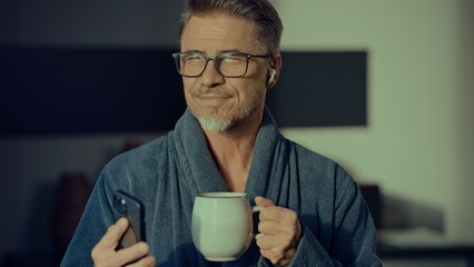 Senior man at home in morning with coffee and smartphone - 754537284