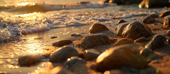 Deurstickers Detailed view of rocks scattered on a sandy beach located near the ocean, glistening under natural light. © FryArt Studio
