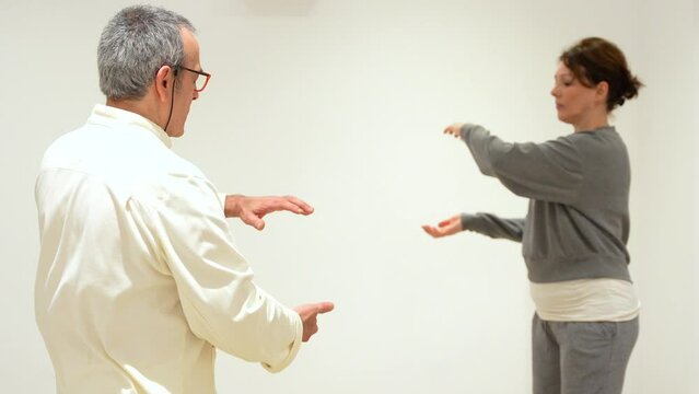 Qi gong instructor and women closing eyes and breathing during a indoor class