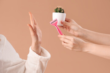 Beautiful young woman rejecting shaving razor on brown background