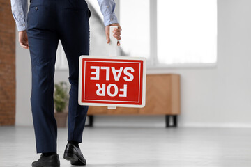 Male real estate agent with FOR SALE in new apartment