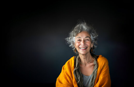Portrait of Charming Senior Aged Female Retiree With Gray Hair, Wrinkles in Orange Cardigan on Dark Black Gray Background Smiling with Teeth Older Woman. Happy Pensioner, Retirement. AI Generated
