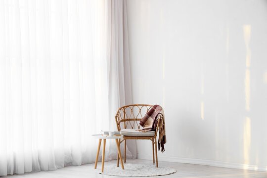 Interior of room with light curtain, armchair and table