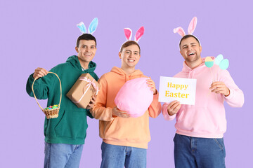 Happy young men in bunny ears celebrating Easter on purple background