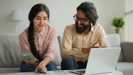 Arabian man Indian woman multiracial couple at home counting euro banknotes salary planning family...